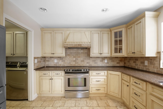 kitchen with premium range hood, tasteful backsplash, washer and dryer, stainless steel range with electric stovetop, and dark stone countertops