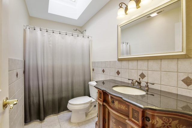 bathroom with tile patterned flooring, curtained shower, toilet, a skylight, and vanity