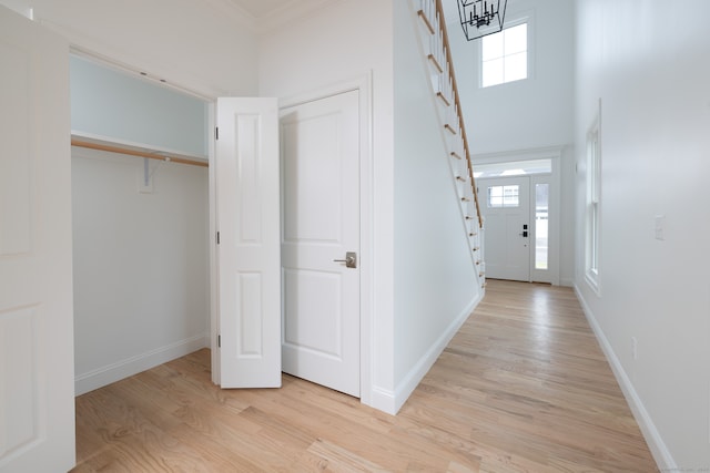 entrance foyer featuring light wood-type flooring, crown molding, and a wealth of natural light