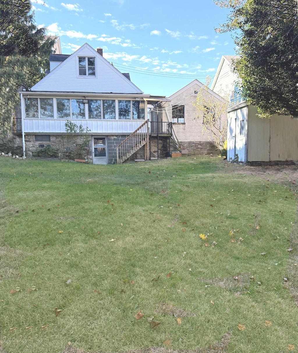 rear view of property with a lawn and a sunroom