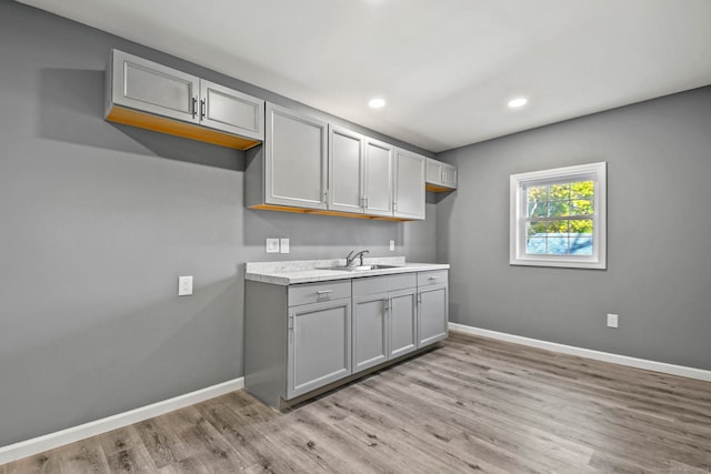 kitchen with gray cabinetry, light wood-type flooring, and sink