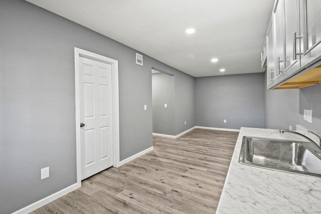 kitchen with white cabinetry, light hardwood / wood-style flooring, and sink