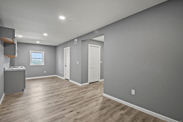 unfurnished living room with sink and light hardwood / wood-style floors