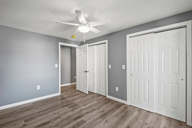 unfurnished bedroom featuring ceiling fan, light hardwood / wood-style flooring, and two closets