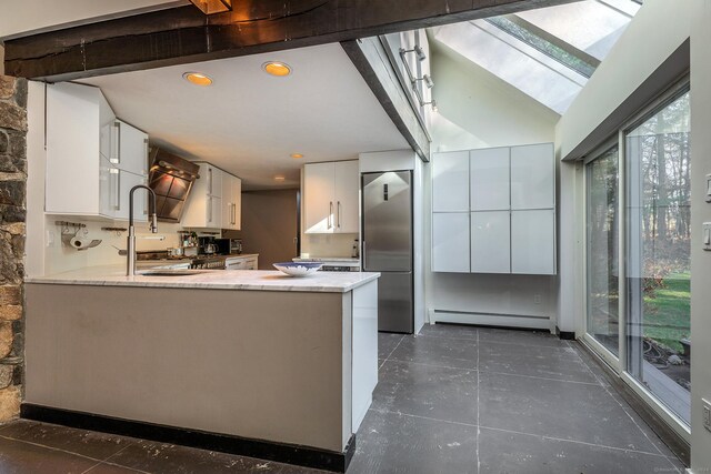 kitchen with stainless steel refrigerator, white cabinetry, sink, a baseboard radiator, and kitchen peninsula