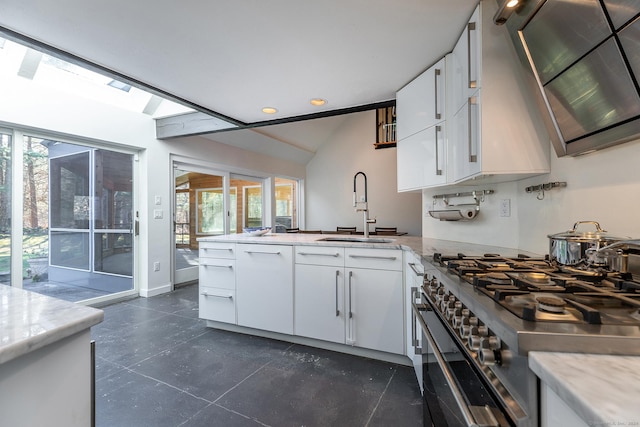 kitchen with kitchen peninsula, gas range, ventilation hood, sink, and white cabinetry