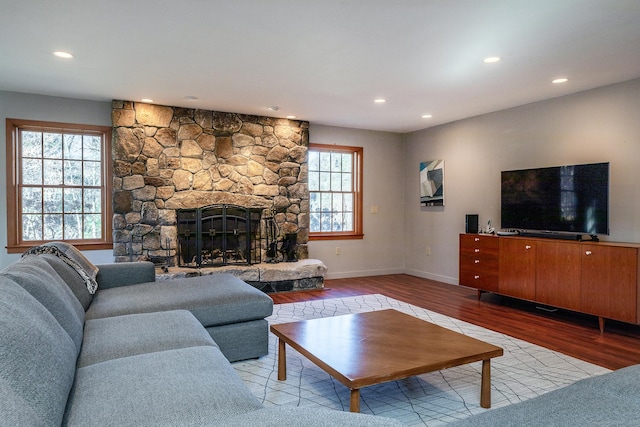 living room featuring a stone fireplace, a wealth of natural light, and light hardwood / wood-style floors