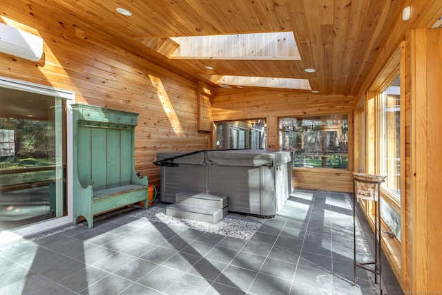 interior space with a jacuzzi, dark tile patterned floors, wooden walls, vaulted ceiling with skylight, and wood ceiling