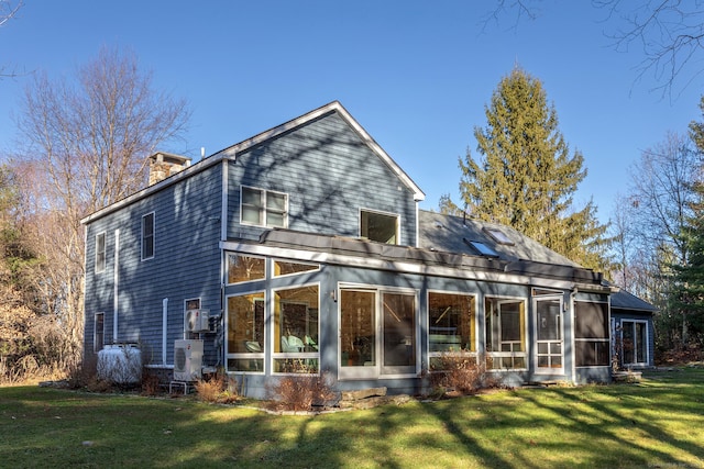 rear view of house with a lawn and a sunroom