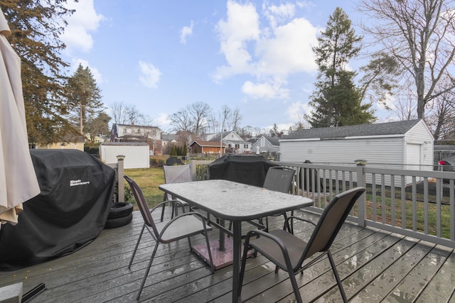 wooden terrace with grilling area, an outbuilding, and a garage