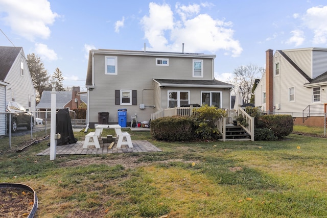 back of property with a lawn, a patio area, and a deck