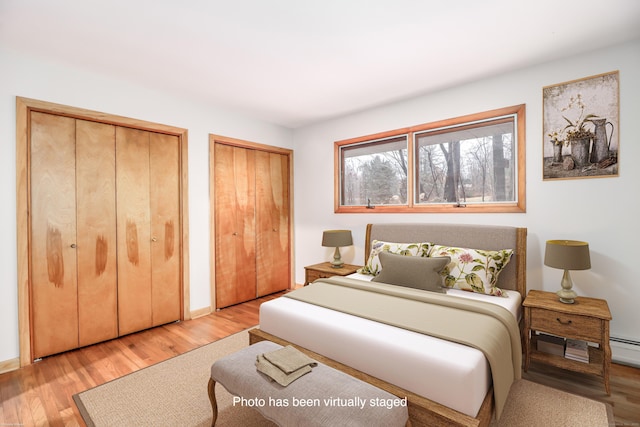 bedroom featuring multiple closets and light hardwood / wood-style floors