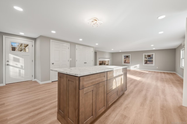 kitchen featuring a kitchen island, light stone counters, and light hardwood / wood-style floors