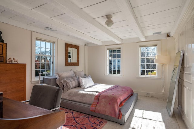 bedroom with visible vents, light carpet, beam ceiling, and baseboards