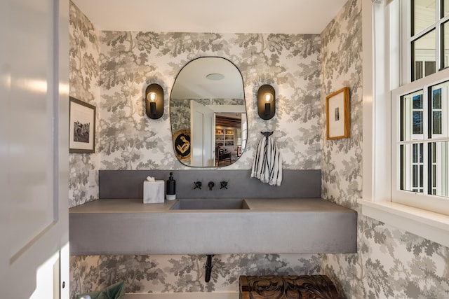 bathroom featuring a sink and wallpapered walls