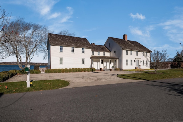 colonial inspired home with a front yard and a water view