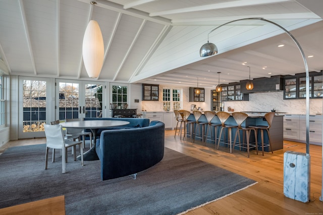 dining area with lofted ceiling with beams, french doors, and light wood finished floors