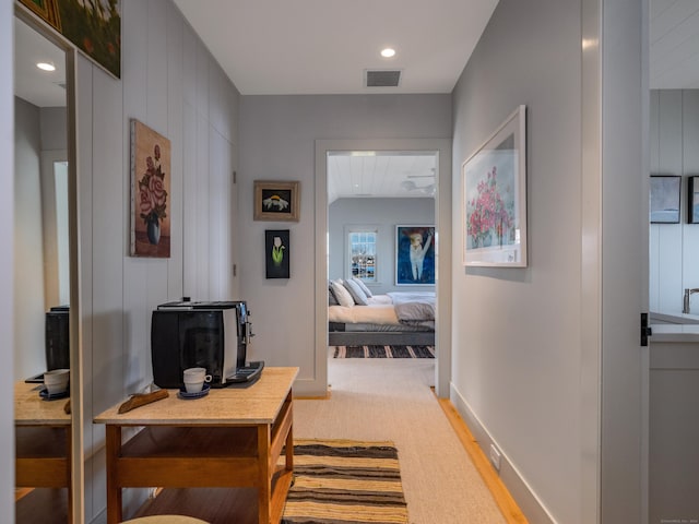 corridor with carpet floors, baseboards, and visible vents