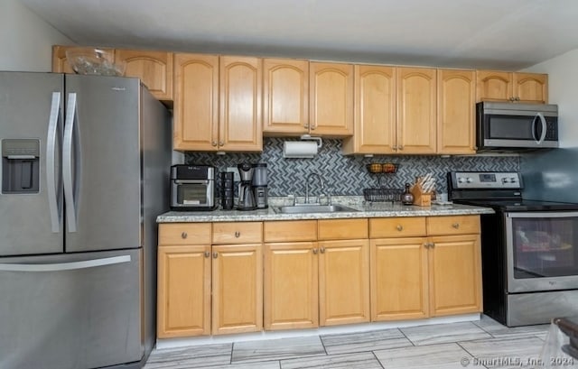 kitchen featuring sink, decorative backsplash, light brown cabinetry, appliances with stainless steel finishes, and light stone counters