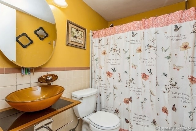 bathroom featuring a shower with shower curtain, toilet, tile walls, and sink