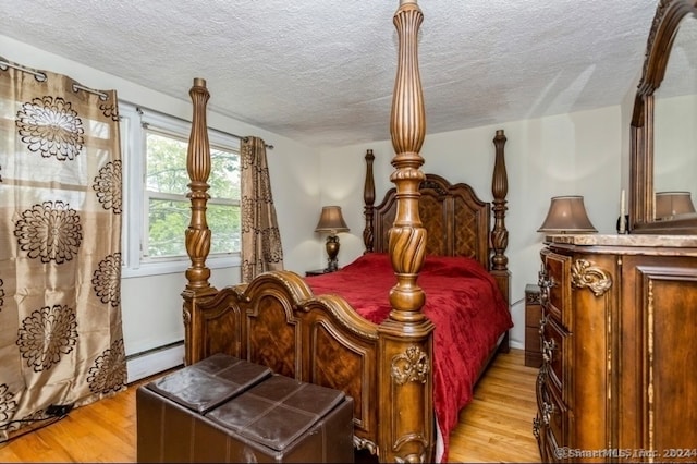 bedroom with a textured ceiling, light wood-type flooring, and baseboard heating