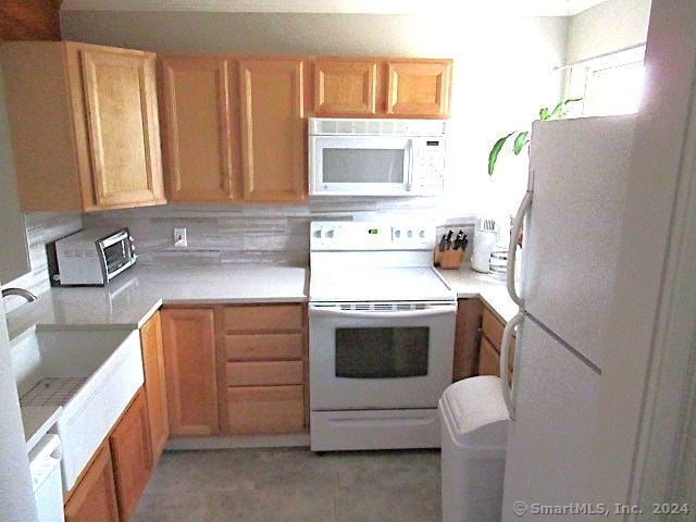 kitchen featuring white appliances, sink, and tasteful backsplash