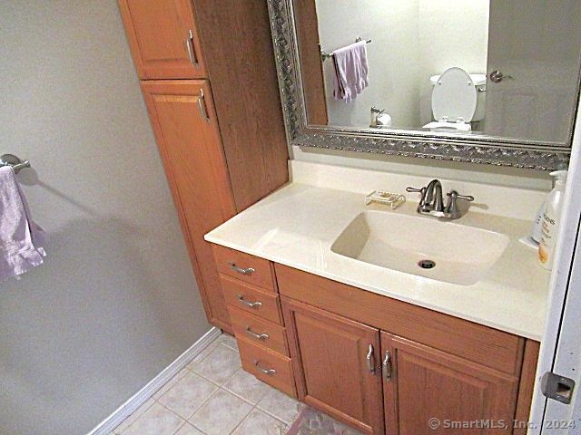 bathroom with toilet, vanity, and tile patterned floors