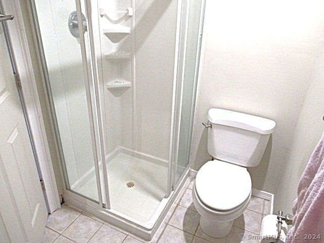 bathroom with toilet, tile patterned flooring, and walk in shower