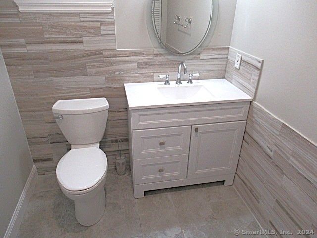 bathroom with vanity, tile walls, and toilet