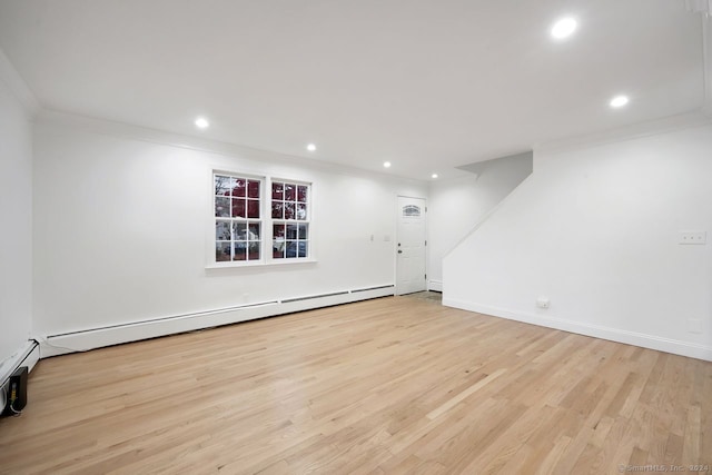 spare room featuring baseboard heating, crown molding, and light hardwood / wood-style flooring