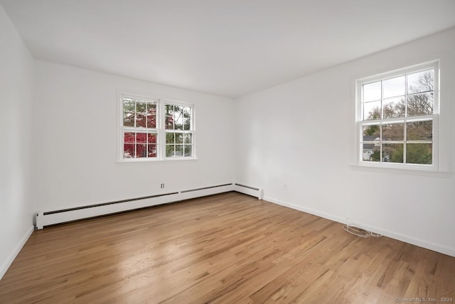 unfurnished room featuring baseboard heating, a healthy amount of sunlight, and light wood-type flooring