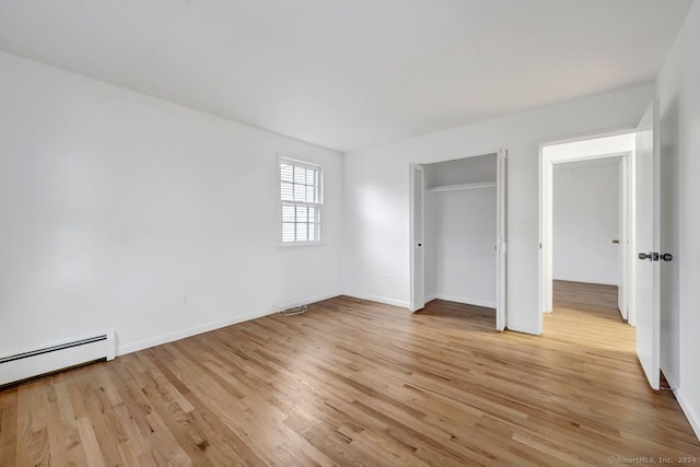 unfurnished bedroom featuring light hardwood / wood-style flooring and a baseboard heating unit