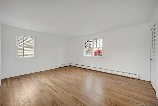 unfurnished room with a baseboard radiator, a wealth of natural light, and light hardwood / wood-style floors