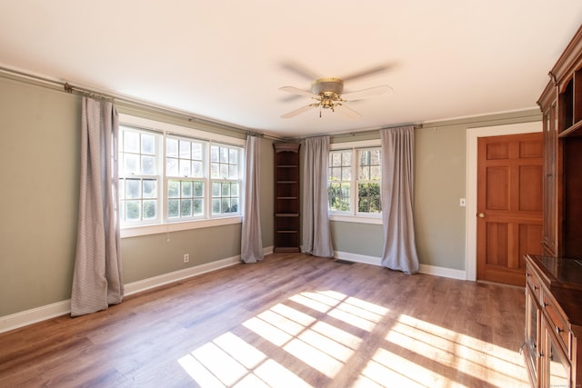 empty room featuring ceiling fan, visible vents, baseboards, and light wood-style floors