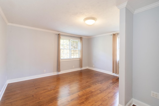 empty room with crown molding, baseboards, and wood finished floors