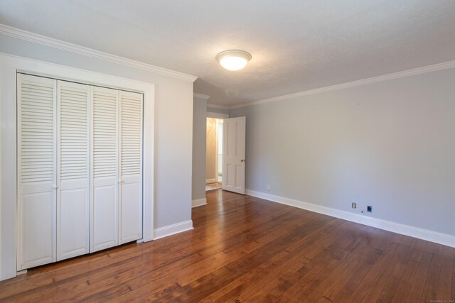 unfurnished bedroom featuring baseboards, ornamental molding, dark wood-style flooring, and a closet