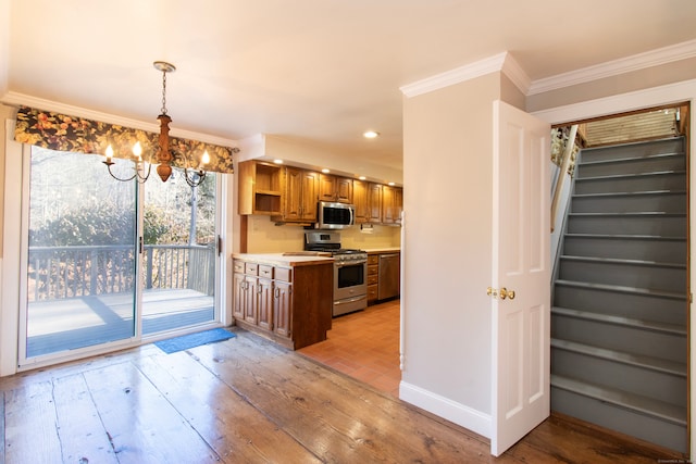 kitchen featuring crown molding, decorative light fixtures, light wood-type flooring, a notable chandelier, and stainless steel appliances