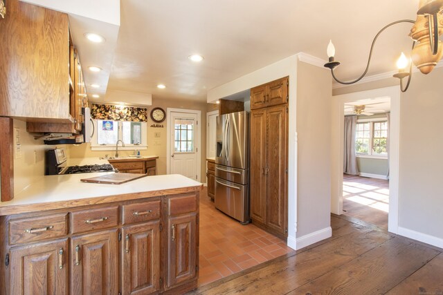 kitchen featuring kitchen peninsula, stove, ceiling fan, sink, and stainless steel fridge with ice dispenser