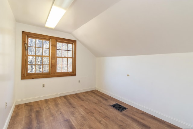 bonus room with baseboards, vaulted ceiling, wood finished floors, and visible vents