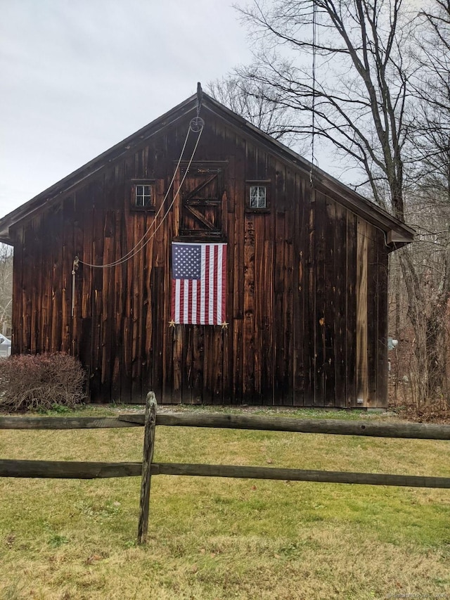 view of barn with a yard and fence