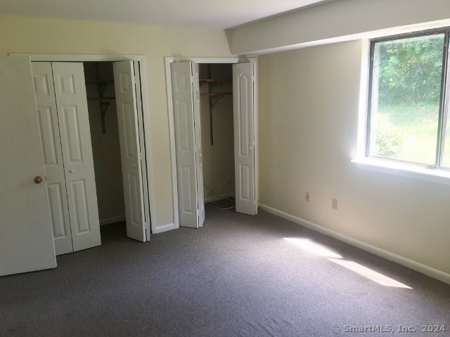 unfurnished bedroom featuring multiple closets and carpet floors