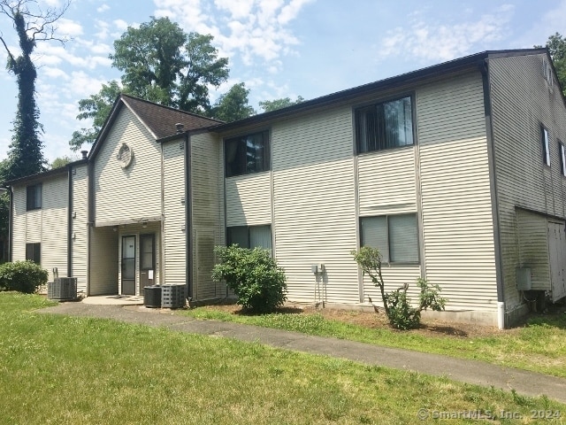 rear view of house featuring central AC unit and a yard