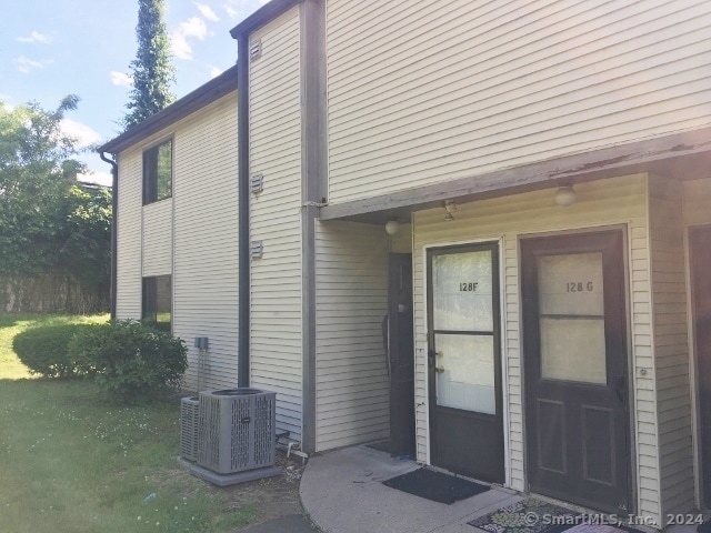 property entrance featuring a yard and central AC unit