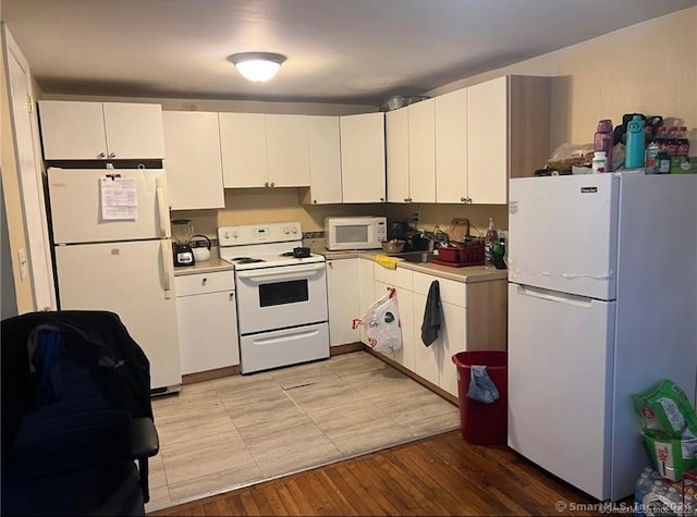 kitchen featuring white cabinets, white appliances, and light wood-type flooring