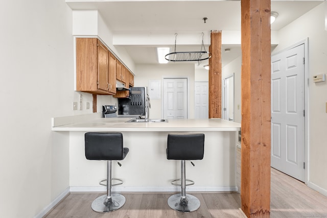 kitchen featuring a kitchen bar, kitchen peninsula, sink, and light hardwood / wood-style floors