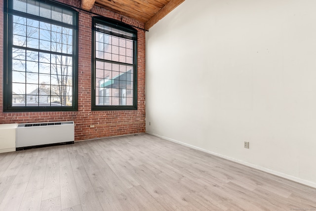 unfurnished room featuring radiator heating unit, wooden ceiling, brick wall, and light hardwood / wood-style flooring