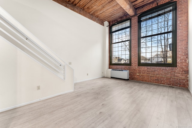 unfurnished room with beam ceiling, wooden ceiling, brick wall, and light hardwood / wood-style flooring