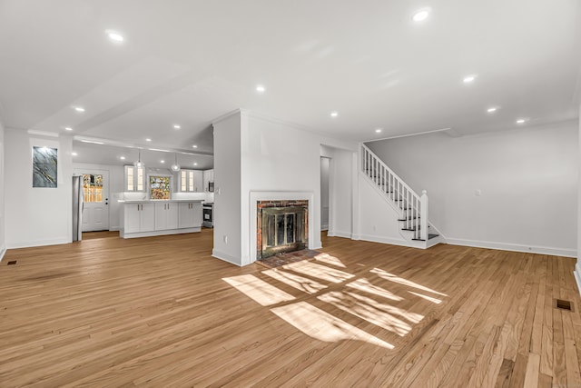 unfurnished living room with crown molding, light wood-type flooring, and a fireplace