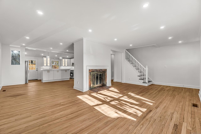 unfurnished living room featuring visible vents, stairway, light wood-style floors, a fireplace, and recessed lighting