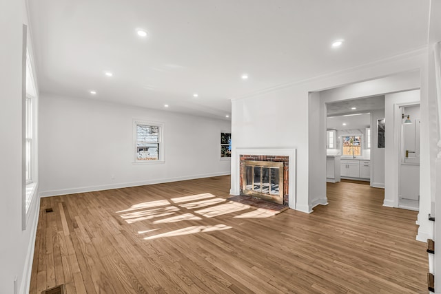 unfurnished living room with sink, light hardwood / wood-style floors, and a brick fireplace